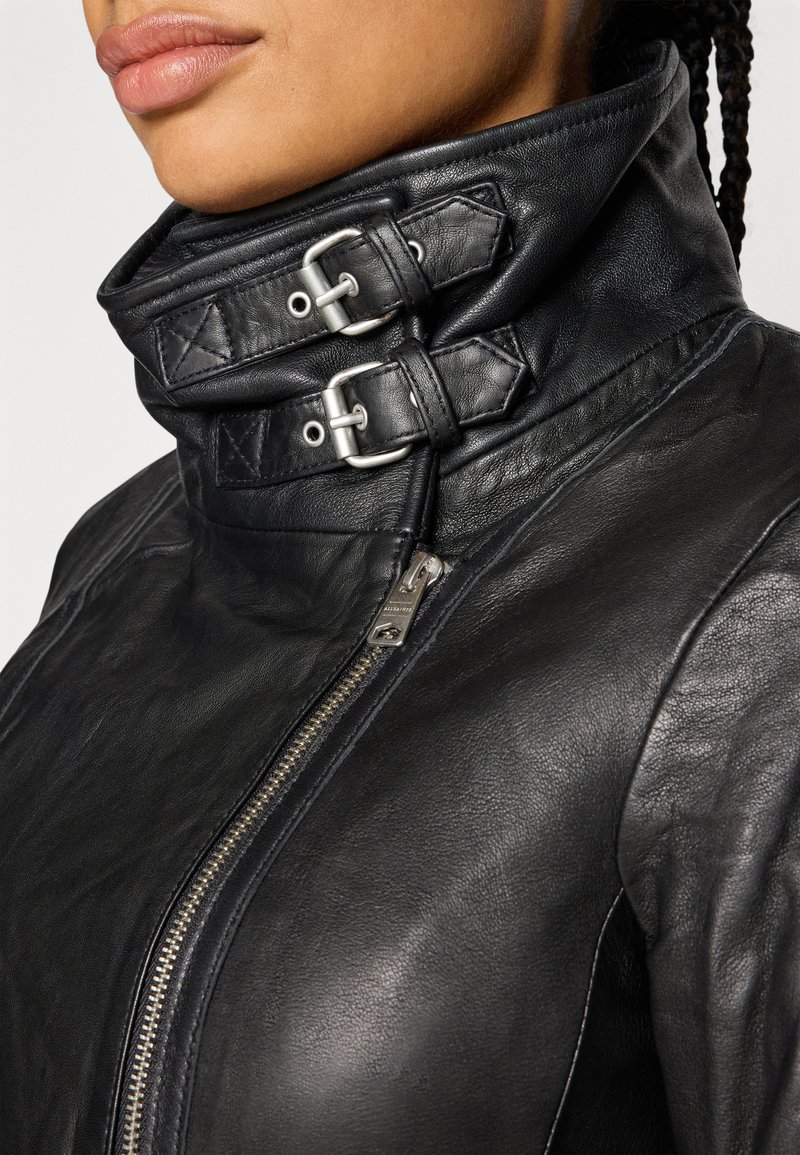 Schwarze Lederjacke mit hohem Kragen, zwei silbernen Schnallen, einem diagonalen Reißverschluss und einer glatten Textur.
