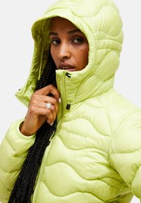 Limegrønne pufferveste med hætte, med en quiltet design og lynlås lukning. "Peak Performance" logo broderet på brystet.