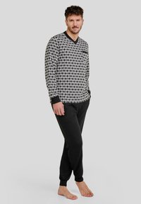 Camiseta de manga larga con un patrón de diamantes en blanco y negro, combinada con pantalones jogger negros con puños elásticos. Material de mezcla de algodón cómodo.