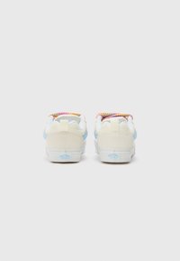 Light blue and cream sneakers with a textured fabric heel and colorful patterned lining. Features white rubber sole and heel pull tab.