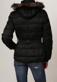 Sort dunjakke med en hætte forsynet med pels, bælte i taljen og quiltet design. Bagfra ses subtil tekstur og en tætsiddende silhuet.