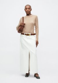 Tan ribbet genser, hvit maxiskjørt med frontspalte, brun belte, brun crossbody-veske og svarte flate sko.