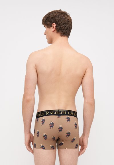 Brązowe bokserki z powtarzającym się wzorem rysunkowych niedźwiedzi w dopasowanych strojach. Czarna gumka w pasie z napisem "POLO RALPH LAUREN". Miękka tkanina.