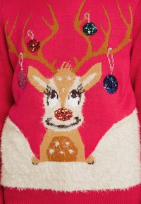Roze gebreide trui met een rendier versierd met pailletten, pluizige witte accenten en gestructureerde bruine en crèmekleurige details.