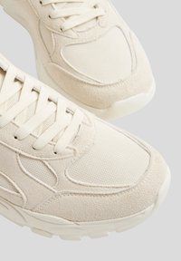 Beżowe sneakersy wykonane z połączenia zamszu o fakturze i materiału canvas, z wyściełanym językiem i zaokrąglonym noskiem. Gumowa podeszwa z przyczepnością.