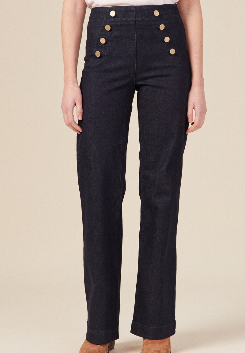 Pantalons taille haute en denim foncé avec une coupe droite et cinq grands boutons dorés à l'avant, présentant une finition lisse et texturée.