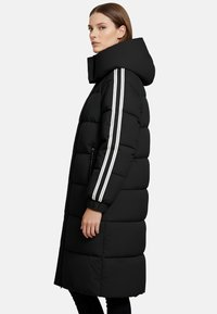 Piumino nero con colletto alto, due tasche laterali e strisce bianche lungo le maniche. Presenta un design trapuntato per l'isolamento.