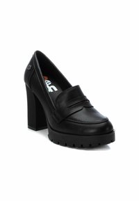 Mocasinés de charol negro con tacón alto, punta redonda, una correa decorativa de cuero y una suela de plataforma gruesa con un diseño texturizado.