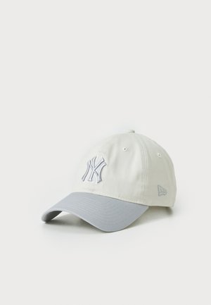 Baseballmütze in hellbeige mit grauem Schirm, verziert mit gesticktem NY-Logo in grau. Hergestellt aus weichem Stoff mit strukturiertem Design.