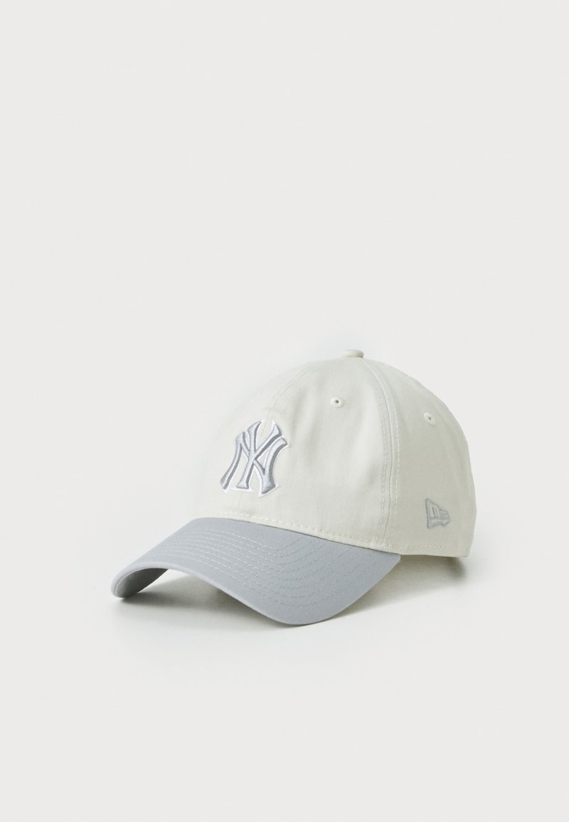 Baseball cap i lys beige med en grå skygge, der har en broderet NY-logo i grå. Lavet af blødt stof med et struktureret design.