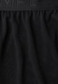 Musta verkkokangas, jossa on teksturoitu pinta ja leveä vyötärönauha, jossa kohopainettu teksti. Kokonaisilme on sileä ja hengittävä.