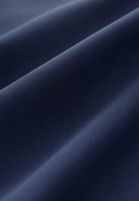 Glatka tamnoplava tkanina s diskretnim dijagonalnim nabora i finim teksturnim detaljima u krupnom planu.