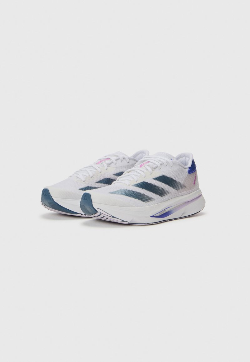 Zapatillas deportivas blancas con acentos azules, parte superior de malla, tres rayas negras en el costado, suela acolchada y detalles rosas en los cordones.