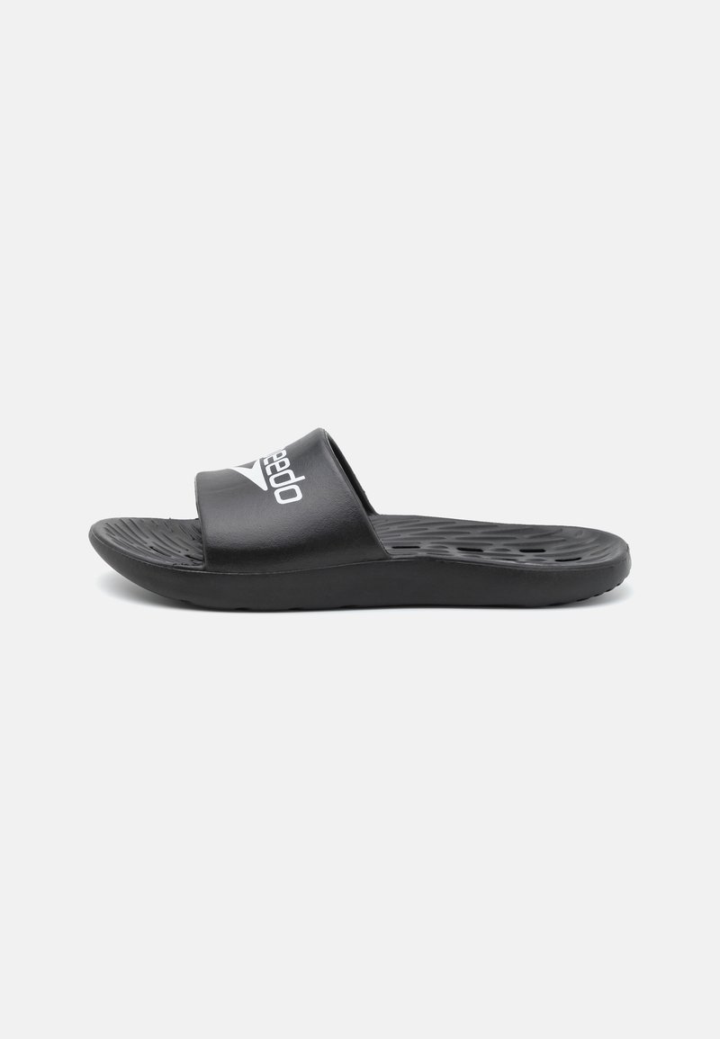 Black slip-on sandal with a textured sole, featuring a wide strap with a white logo. Made of synthetic material. Flat design.