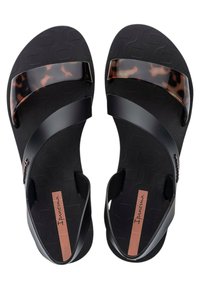 Sandalias negras con una tira de carey brillante. Presenta una base negra texturizada y un diseño flexible. Logo de la marca visible en la plantilla.