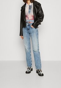 Svart fusk läder bikerjacka, pastellfärgad abstrakt blus, ljusblå raka jeans, rutiga plattformsskor med tjocka sulor.