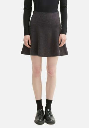 Jupe évasée en tissu gris foncé, avec une taille ajustée et une texture lisse, associée à des chaussures noires et des chaussettes.
