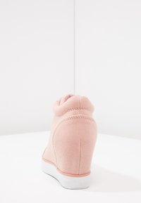 Růžová látková bota s vysokým límcem, texturovaným povrchem a bílou gumovou podrážkou. Vyznačuje se elegantním, zaobleným designem s jemným prošíváním.