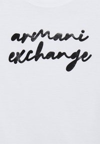 Camiseta de algodón blanca con un logo negro brillante de "armani exchange" en una fuente cursiva, situado en el centro del frontal.