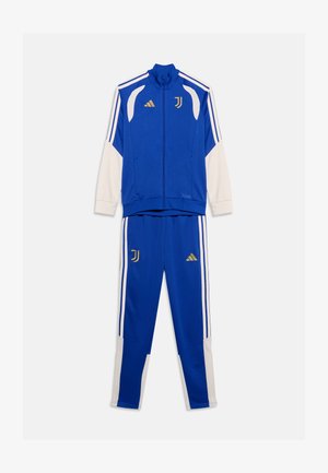Chándal azul y blanco de Adidas Juventus con logos dorados, chaqueta con cremallera y pantalones a juego sobre un fondo blanco liso.