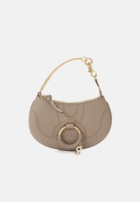 Bolso de mano de piel color beige con forma curva, diseño grabado, herrajes dorados y un acento circular trenzado. Incluye una correa de cadena.