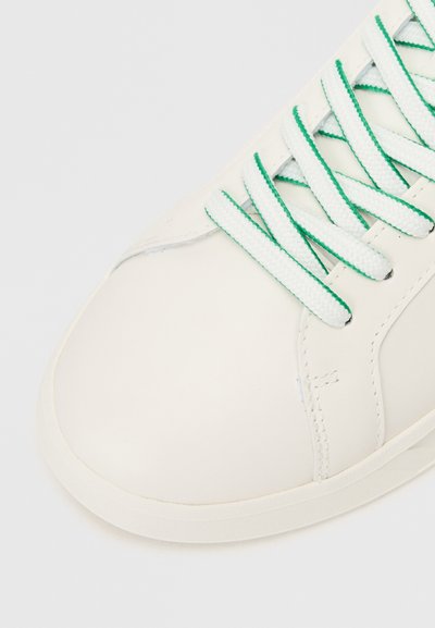 Λευκό sneaker με λείο δέρμα στην επάνω πλευρά, πράσινα κορδόνια και στρογγυλή μύτη. Περιλαμβάνει διακριτές ρα�φές και υφασμένη καουτσούκ σόλα.