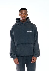 Felpa oversize grigia scura con cappuccio regolabile, tasca frontale e scritta "MULTIPLY" in bianco. Tessuto morbido e testurizzato con polsini a costine.