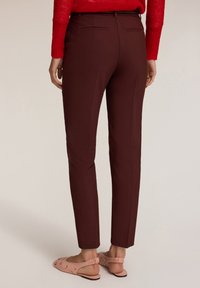Bordeauxkleurige op maat gemaakte broek met een slim fit en subtiele achterzakken, gecombineerd met lichtroze versierde slingback schoenen. Getextureerde, aansluitende stof.