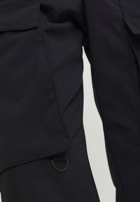 Mörkblå cargobyxor med en slät textur, utrustad med en sidoficka med lock och en metall D-ring fäste.