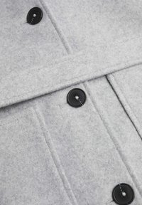 Grå ullblandningstyg har en strukturerad design med svarta knappar, synliga sömmar och en slät yta.