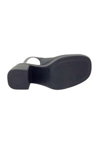 Suola di scarpa in gomma nera, caratterizzata da un motivo testurizzato, forma quadrata e un design con tacco leggermente rialzato. Parte superiore liscia con una fascia stretta.