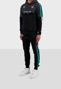 Conjunto de sudadera con capucha y pantalones jogger de tejido, con acentos grises, rayas turquesas y logos. La sudadera tiene un bolsillo frontal; los pantalones jogger tienen bolsillos laterales.