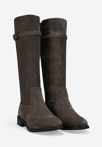 Botas de ante marrón oscuro, altas, con tacones bajos en bloque, cremallera lateral y correas decorativas con hebilla cerca de la parte superior.