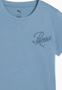 Lichtblauwe katoenen t-shirt met een ronde hals. Heeft een donkerblauwe geborduurde "Puma" logo en een klein icoon op het linkerbovenbeen.