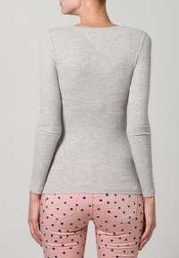 Light gray long-sleeve top in a ribbed texture, paired with pink pants featuring blue polka dots and back pockets.