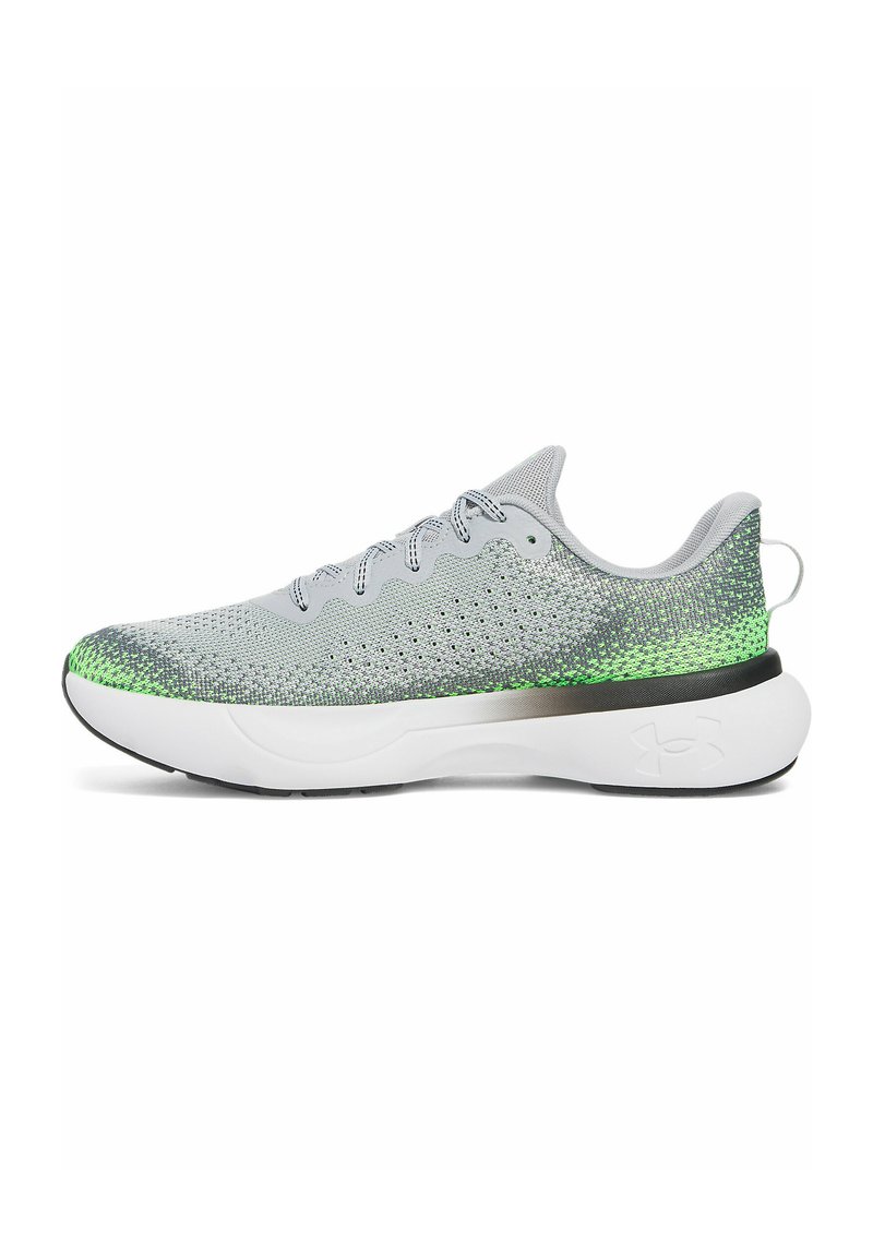 Zapato deportivo gris con parte superior de malla transpirable y acentos verdes. Cuenta con una suela blanca acolchada y detalles reflectantes.