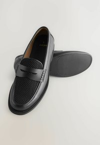 Zwarte loafers met een textuurbovenkant van gaas en gladde leren accenten. Voorzien van een vlakke zool en een subtiele logo-detail op de voorkant.
