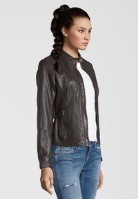 Braune Lederjacke mit taillierter Passform, hohem Kragen und durchgehendem Reißverschluss. Verfügt über Seitentaschen und gerippte Akzente an den Schultern.