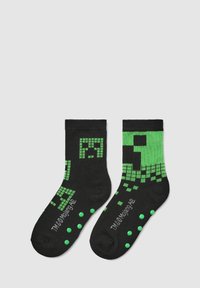 Calze nere con motivo pixelato verde e punti antiscivolo testurizzati sulle suole. Presentano un polsino a coste per una vestibilità sicura.