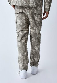 Camouflage cargo-broeken in gedempte grijstinten, met meerdere zakken en een relaxte fit. De stof heeft een gestructureerd, patroonontwerp.