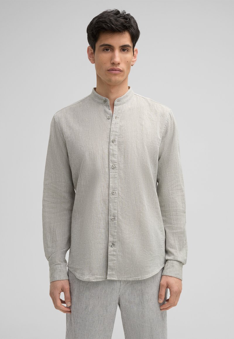 Helles graues Langarmshirt mit Stehkragen, Knopfleiste vorne und dezentem Strukturmuster. Kombiniert mit gestreiften Hosen.