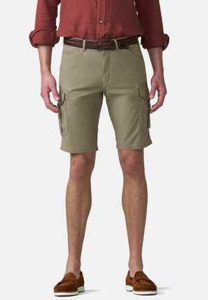 Mann trägt beige Cargo-Shorts mit Front- und Seitentaschen, einen braunen geflochtenen Gürtel, ein rostfarbenes Langarmshirt und braune Slipper.