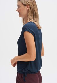 Top ribbed blu navy con maniche corte e dettaglio in vita arricciato, realizzato in un tessuto morbido, presenta una vestibilità comoda e un collo rotondo.