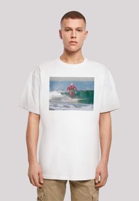 Balta per didelis t-shirt'as su spalvinga banglenčių grafika, vaizduojanti banglentininką rožiniu wetsuit'u, važiuojantį banga. Kasdienis kirpimas, trumpomis rankovėmis.