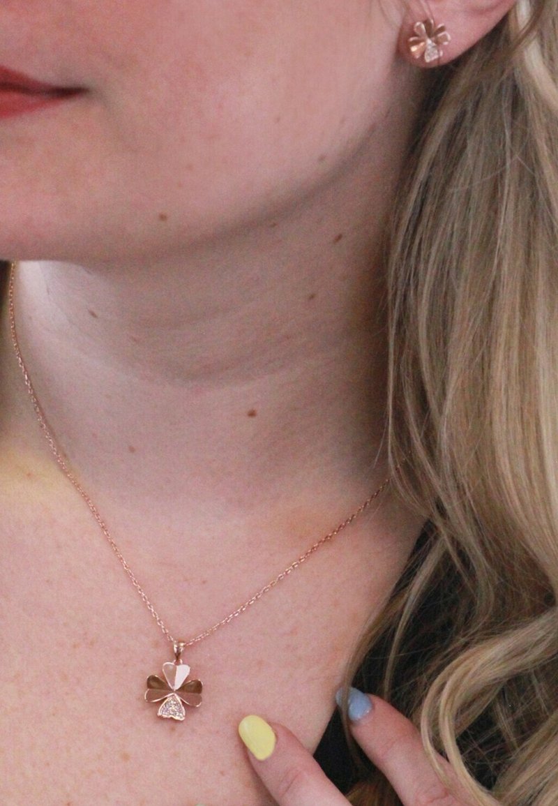 Collana in oro rosa con ciondolo a forma di trifoglio con foglie lisce e texturizzate. Orecchini a bottone a forma di trifoglio in oro rosa coordinati.