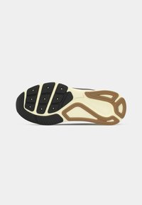 Suola di una scarpa sportiva con motivo di battistrada nero, crema e marrone su uno sfondo bianco.