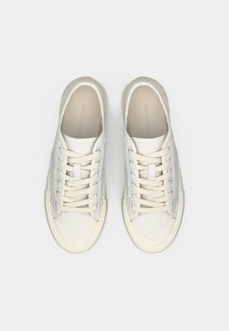 Baskets en toile de couleur blanc cassé avec une finition texturée, design à bout rond, semelle en caoutchouc crème contrastante et lacets plats.