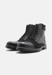 Botas negras hasta el tobillo hechas de cuero y gamuza, con punta redonda, cierre de cordones, cremallera lateral y suela de goma texturizada.