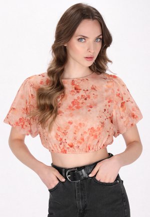 Blomsterprint cropped top i lyse fersken med korte puffærmer, samlet kant og subtil glans; parret med højtaljede sorte jeans.