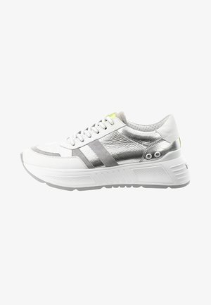 Witte en zilveren lage sneakers met een dikke zool, vetersluiting aan de voorkant en een klein neongele accent op de tong en hak.